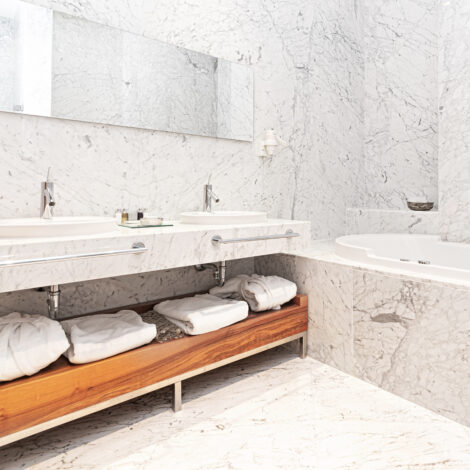beautiful interior of a modern white marble hotel batroom with bathtube and towels.