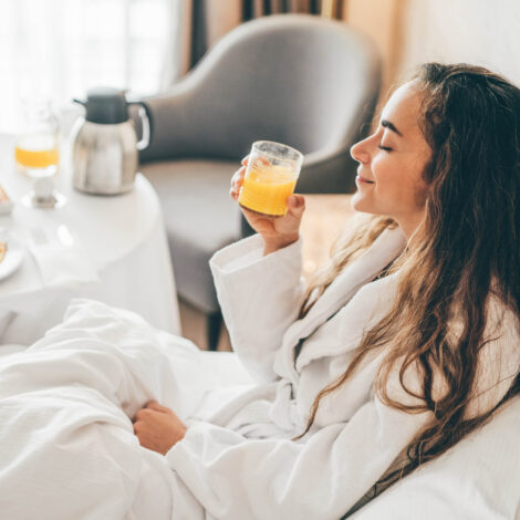 Woman eating breakfast in the hotel room. Room service breakfast in hotel room.